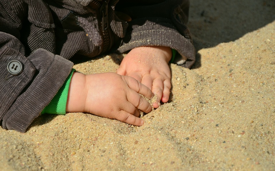Handjes van een kindje voelen aan het zand