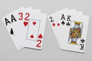 Twee stocks met speelkaarten (grootletterspelkaarten en braillespeelkaarten) op een lichtgrijze ondergrond. De kaarten zijn als een waaier uitgespreid.